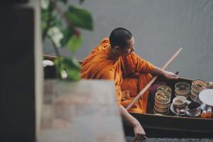 a monk in a boat with food on it at Bansuwan Homestay in Amphawa