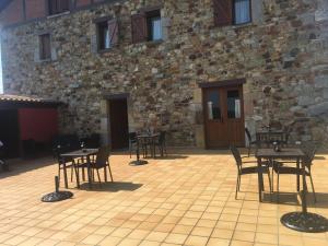 a patio with tables and chairs in front of a stone building at Posada El Nozal in Seña