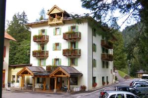 a large white building with balconies and cars parked in a parking lot at Hotel Zanella in Peio Fonti