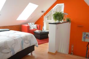 a bedroom with orange walls and a bed and a chair at Ferienhaus Luzia in Darscheid