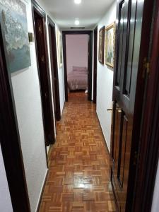 a hallway with a room with a bed and a wooden floor at Apartamento zona Palacio de las Dueñas y las Setas in Seville