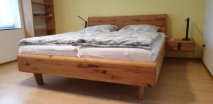 a large wooden bed with white sheets and pillows at Gästezimmer Junglas in Bornheim