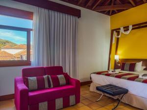 a bedroom with a bed and a chair and a window at La Casona del Patio in Santiago del Teide