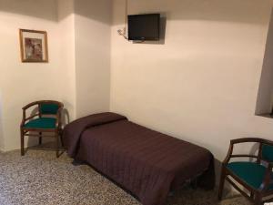 a bedroom with a bed and two chairs and a tv at Al Podere del Nonno Romolo in Sansepolcro