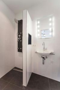 a white bathroom with a sink and a window at Amsterdam Beach Zandvoort Studio s in Zandvoort