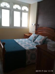 a bedroom with a bed with a blue comforter and two windows at Km 0 Camiño Ingles Benito Vicetto, 14 in Ferrol