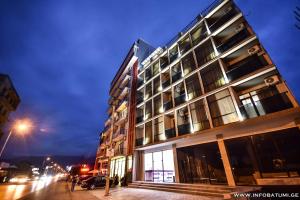 a tall building on a city street at night at Hotel Wave in Batumi