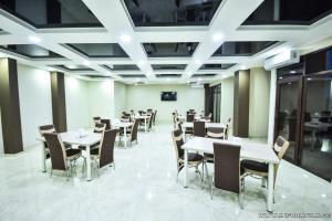 a dining room with tables and chairs and a screen at Hotel Wave in Batumi