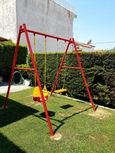 a red swing set on the grass in a yard at Babis House in Nea Vrasna