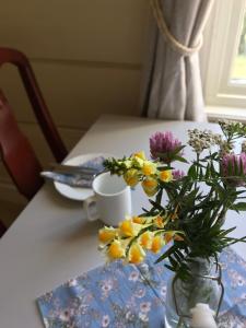 a table with a vase of flowers and a cup at Heidal Gjestgiveri AS in Nedre Heidal