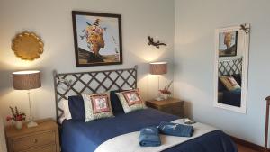um quarto com uma cama azul e duas mesas de cabeceira em Art Gallery Guest House em Haenertsburg