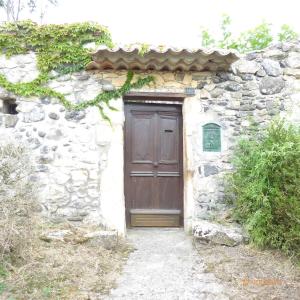 een stenen gebouw met een houten deur erop bij Malarias 1 in Rochemaure