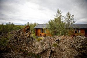 a log house with a large rock in front of it at Vogafjós Farm Resort in Myvatn