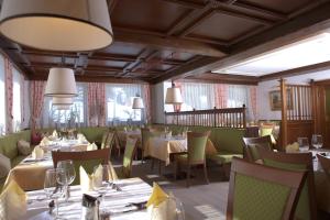 uma sala de jantar com mesas, cadeiras e janelas em Hotel Waidmannsheil em Flachau