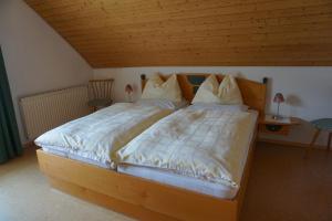 ein großes Bett in einem Schlafzimmer mit Holzdecke in der Unterkunft Haus Waldblick in Weissensee