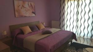 ジャッレにあるAppartamento Etnaのベッドルーム1室(紫のシーツが敷かれたベッド1台、窓付)