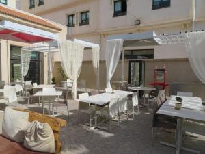 un patio con tavoli e sedie bianchi e ombrelloni di ibis Tlemcen a Tlemcen