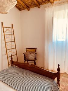 a bedroom with a bed and a chair and a window at Casas de Mértola - N. Sª das Neves in Mértola +6 photos