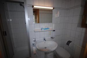 biała łazienka z umywalką i lustrem w obiekcie Pension Tirol w mieście Nauders