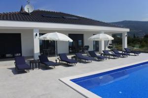 a group of chairs and umbrellas next to a swimming pool at Villa Orao in Kastel Novi