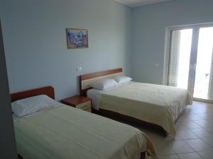 a bedroom with two beds and a window at Olympian Rooms in Dhërmi +35 photos