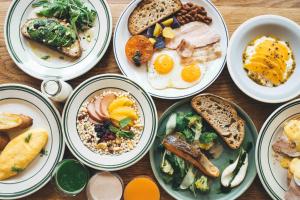 een tafel met borden ontbijtproducten bij Hotel Noum OSAKA in Osaka