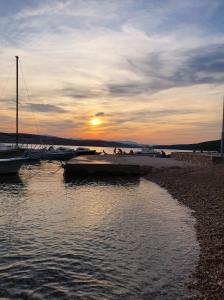 a group of boats docked on a beach at sunset at Apartman Dora in Šmrika