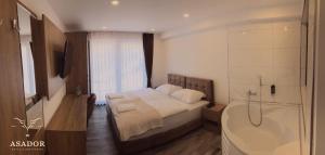 ein Schlafzimmer mit Bett, Badewanne und Waschbecken in der Unterkunft ASADOR Hotel & Restaurant GmbH in Netphen