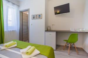 a room with a bed and a desk and a green chair at Room Elelina in Cres