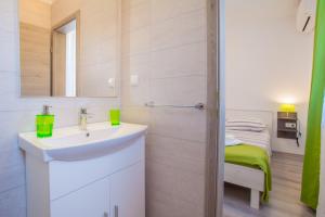 uma casa de banho branca com um lavatório e um espelho em Room Elelina em Cres