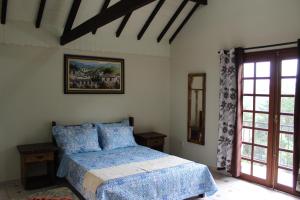 a bedroom with a bed with blue sheets and a window at Chalé Topázio in Monte Verde