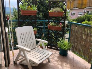 a white chair sitting on a balcony with potted plants at Apartment Sofia with terrace & parking in Bratislava