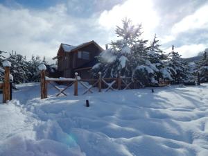 a cabin in the snow with a pile of snow at Cabañas Wenuray in Villa Meliquina