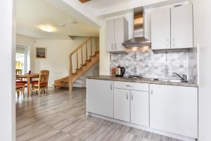 a kitchen with white cabinets and a dining room at Vila GULBĖS TAKAS in Šventoji
