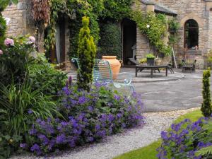 un banco sentado en un jardín con flores púrpuras en Whitmore, en Lancaster