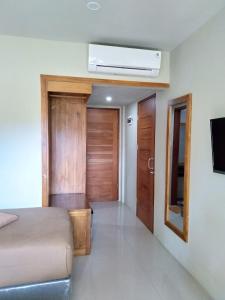 Hastina Hotel Lombok في ماتارام: غرفة نوم بسرير وتلفزيون في غرفة