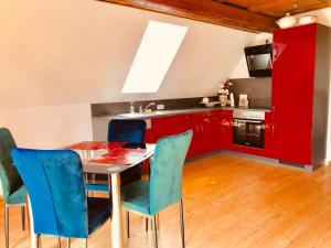 una cocina con armarios rojos y una mesa con sillas azules en Appartment Ivonete, en Wettringen