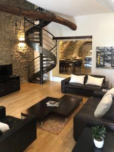 una sala de estar con muebles negros y una escalera de caracol. en Villa Authentique et Architecturale - Centre Ville, en Forcalquier