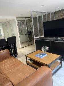 een woonkamer met een bank, een tafel en een tv bij Appartement Design Centre ville in Saint-Tropez
