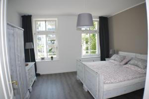 1 Schlafzimmer mit einem weißen Bett und 2 Fenstern in der Unterkunft Ferienwohnung Busch in Leipzig