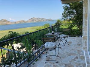 balcón con mesa, sillas y vistas al agua en Skadar lake house Bobija, en Podgorica