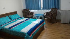 a bedroom with a bed and two chairs at Seek Place in Tainan