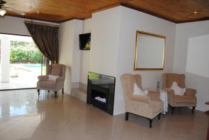 ein Wohnzimmer mit einem Kamin, Stühlen und einem TV in der Unterkunft Villa D este in Kimberley