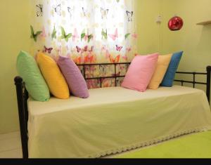 a bed with colorful pillows on it with a window at 2 BR Medina Dollar Landed Homestay Cheras MRT Link in Cheras
