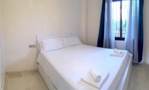 a bedroom with a white bed with two towels on it at Modern Ground Floor Calanova Golf Apartment in La Cala de Mijas +23 photos