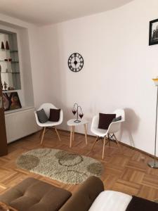 a living room with two chairs and a clock on the wall at Xenopol Central in Sibiu