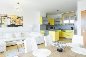 salon i kuchnia z białymi meblami i żółtymi szafkami w obiekcie MF Club 218 Palazzo Wellness Apartment w Siófoku