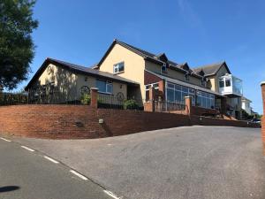 a house with a brick fence in front of a street at Lakeland Guest House in Pembroke Dock