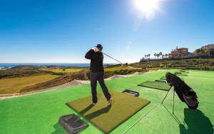 a man swinging a golf club on a golf course at Modern Ground Floor Calanova Golf Apartment in La Cala de Mijas