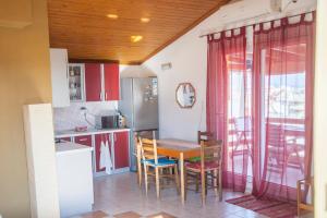 a kitchen with red cabinets and a table and chairs at Attic Anemoessa in Alexandroupoli